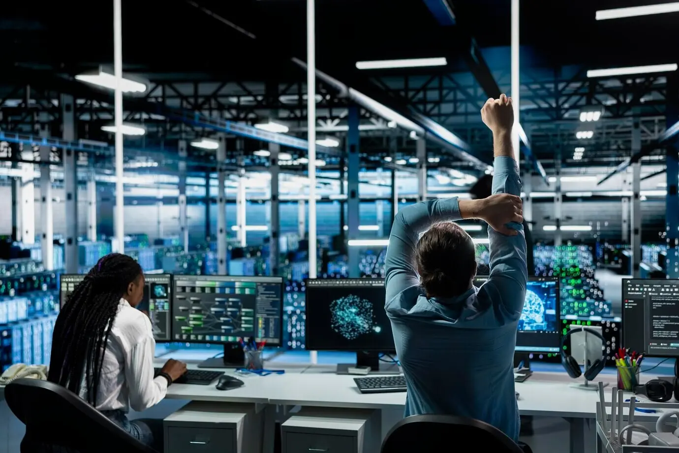 Científico de la computación en un centro de datos relajando las articulaciones para combatir la fatiga sedentaria después de trabajar largas horas