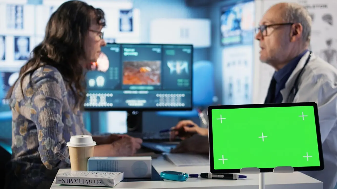 Paciente mayor y especialista en una visita de revisión junto a una pantalla de croma.